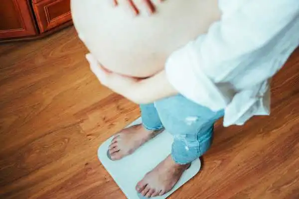 Image of woman weighing herself and experiencing weight gain through pregnancy Beccles